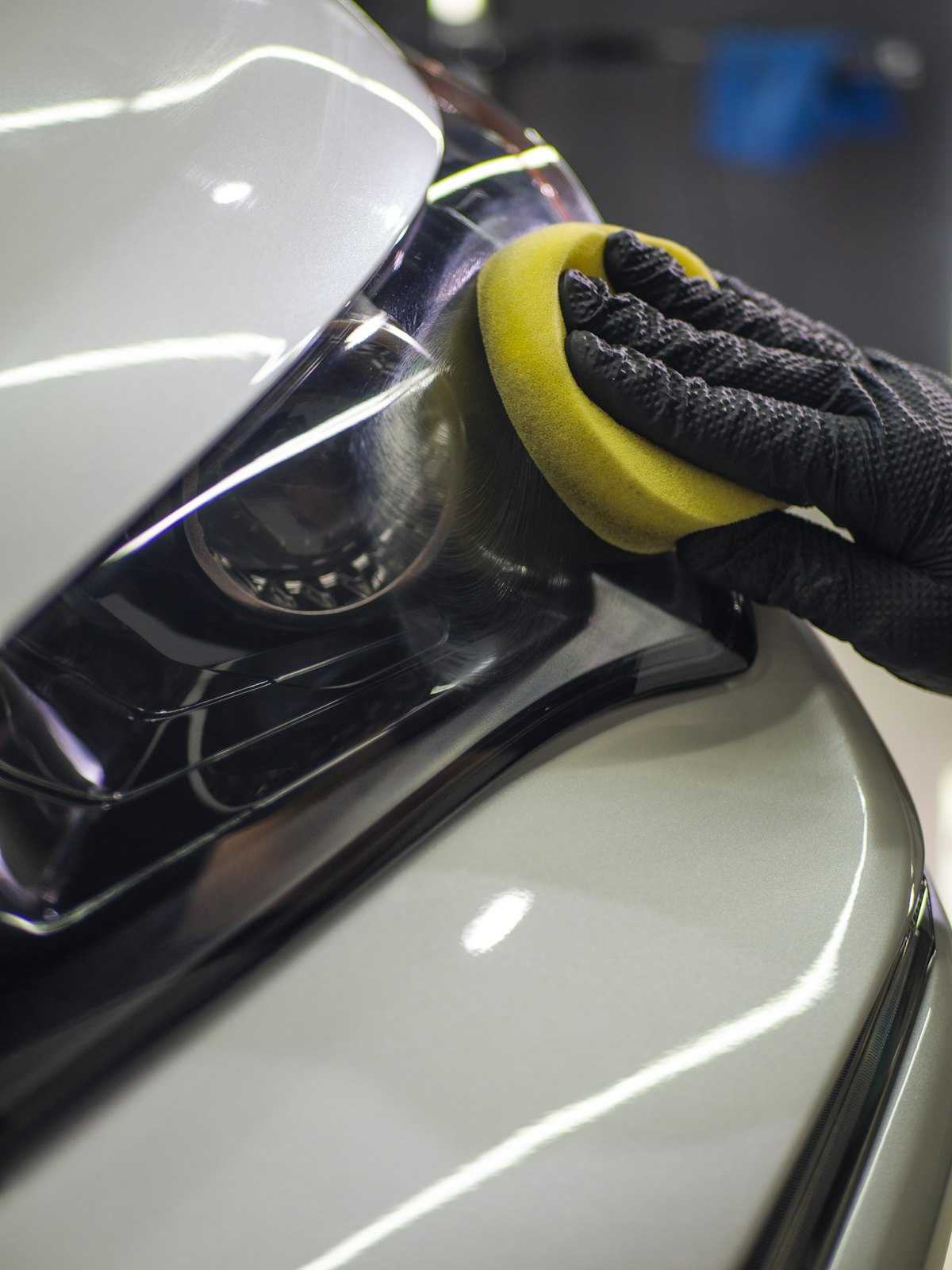 A gloved hand polishing a car panel to a gloss
